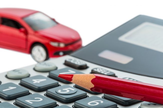 a car and a red pen lying on a calculator. cost of gasoline, wea