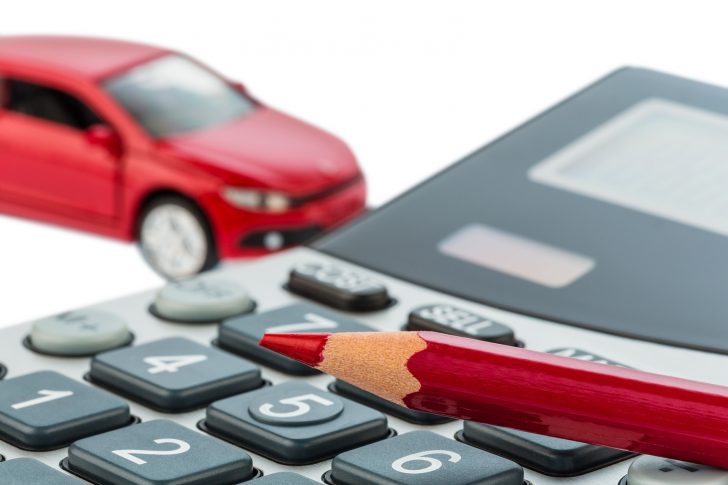 a car and a red pen lying on a calculator. cost of gasoline, wea